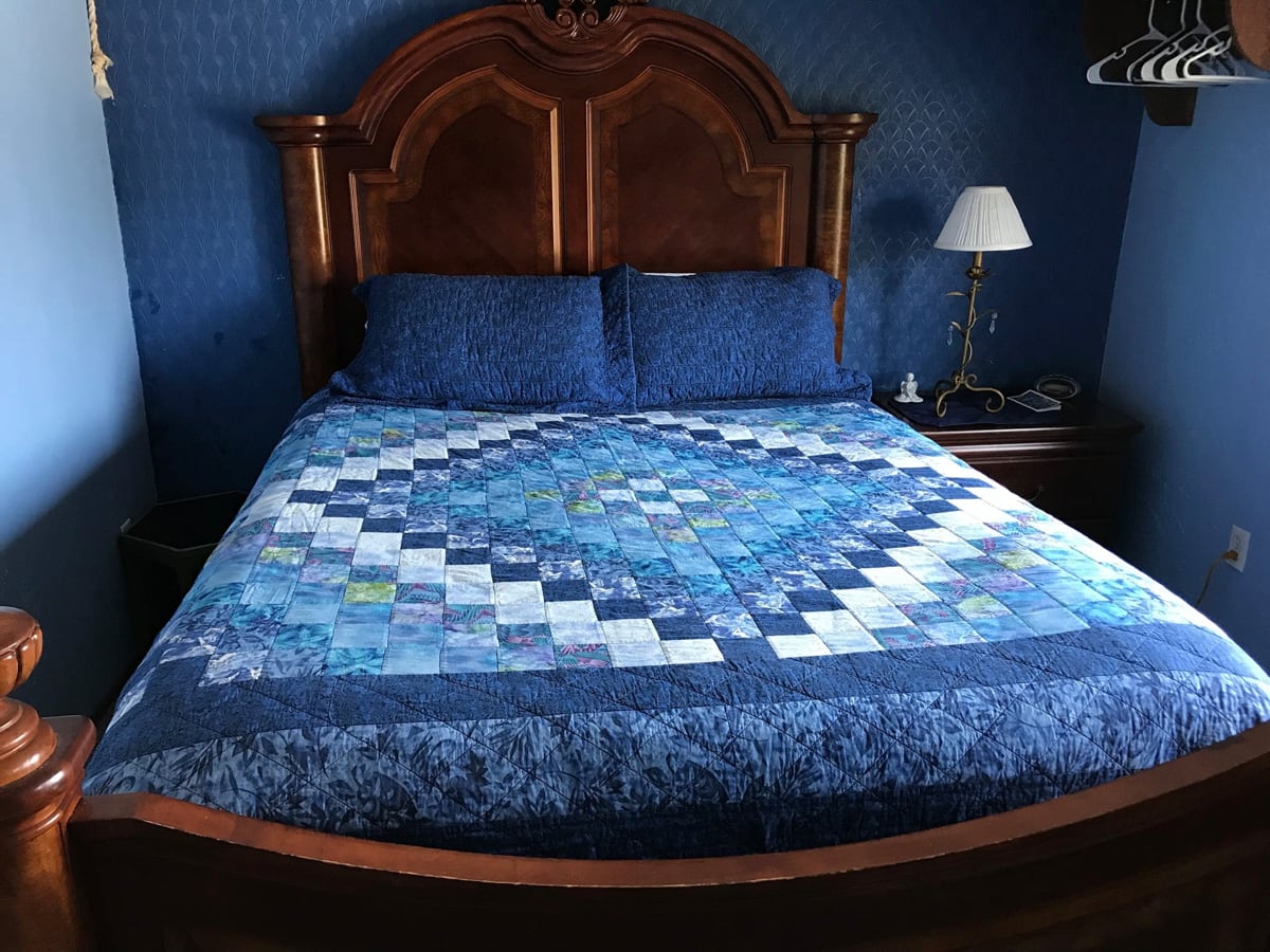 Queen bed with handmade blue quilt